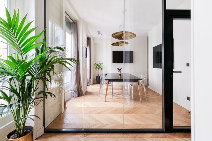 Espace de travail sous verrière, plantes et mobilier clair, dans les bureaux de Core Group.