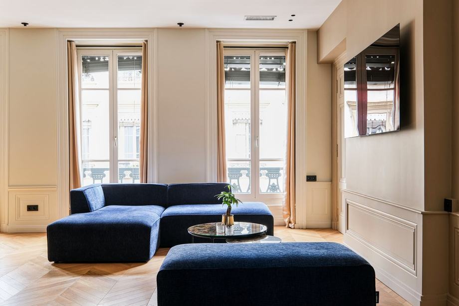 Salon d’accueil aux moulures et canapé bleu nuit, dans les bureaux de Core Group à Lyon.