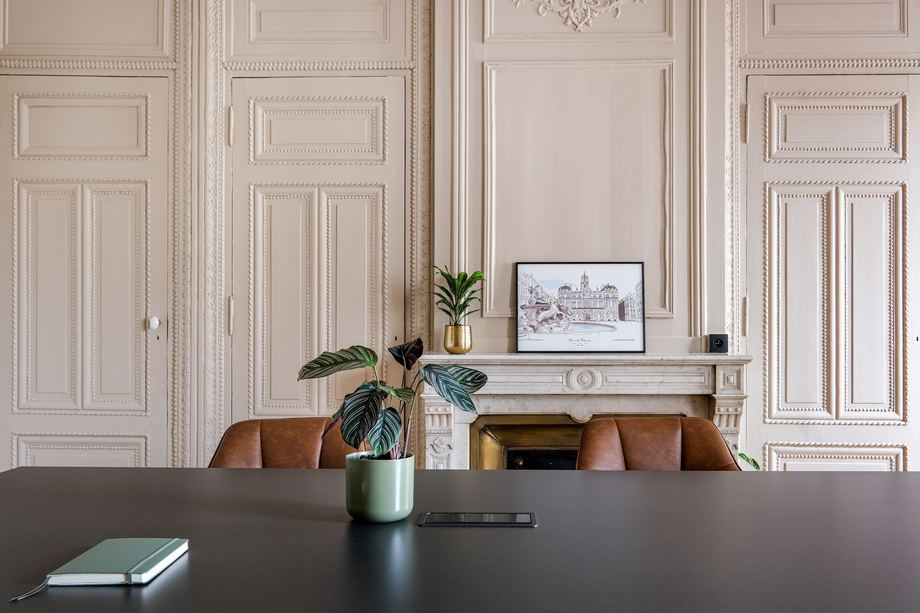 Salle de réunion aux boiseries claires et cheminée de marbre, fauteuils en cuir, au siège de Core Group.